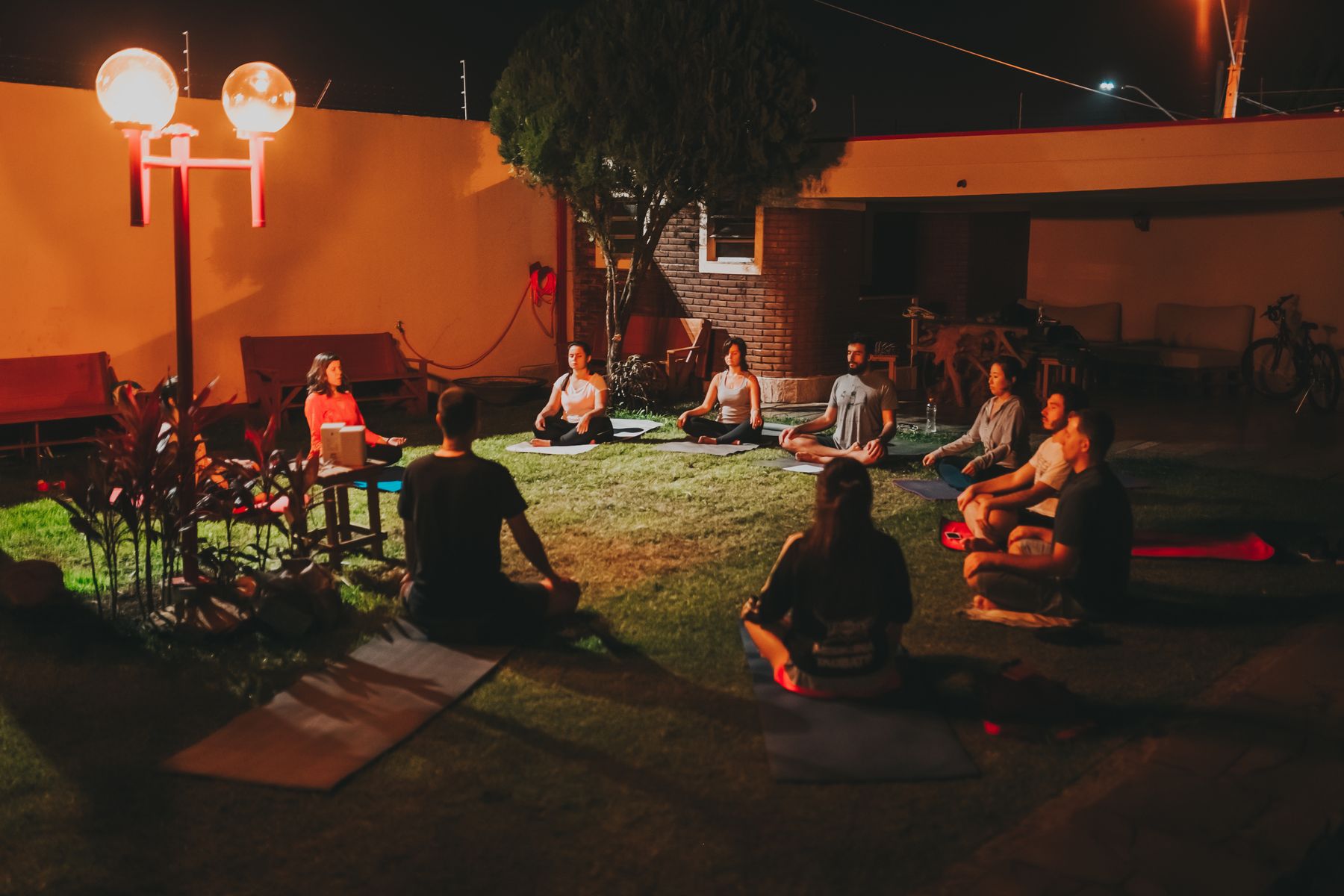 Grupo meditando al aire libre de noche con luz cálida